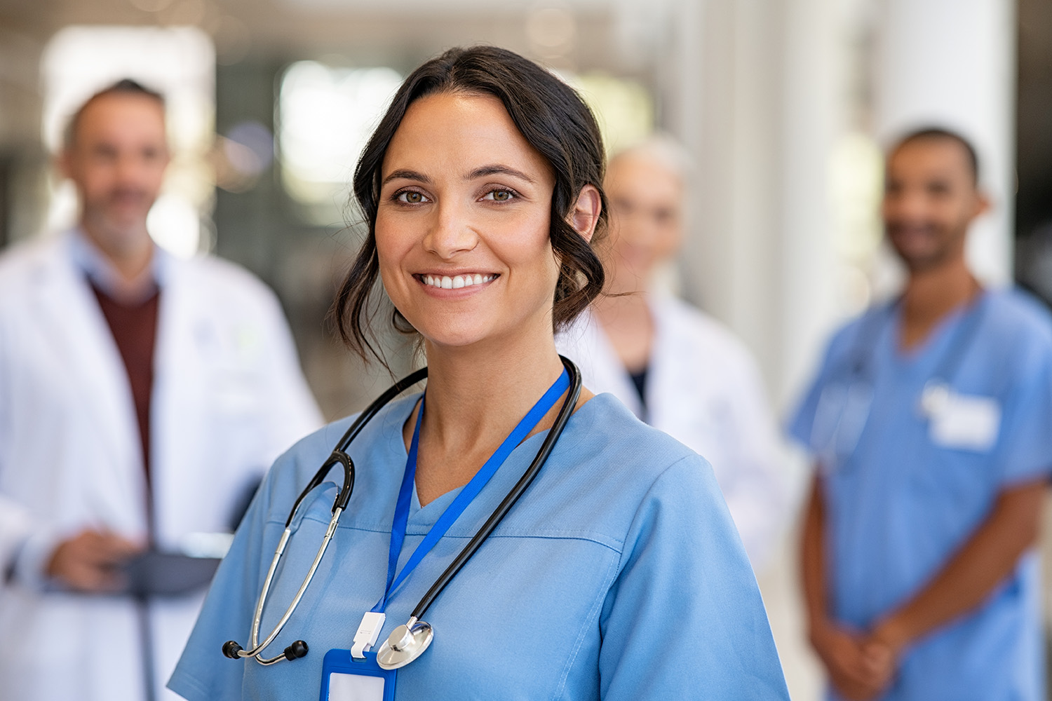 Nurse in uniform with healthcare team in background.