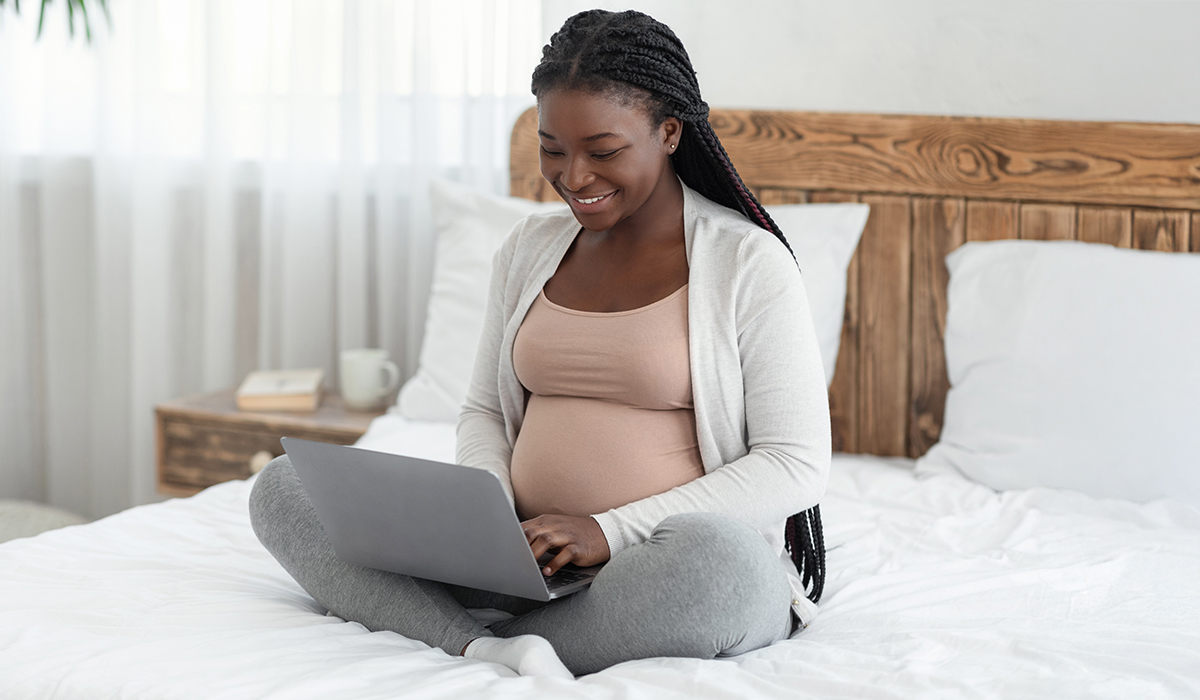Cheerful Expecting Mother Using Laptop at Home, Smiling Pregnant Using the Internet or Working Remotely