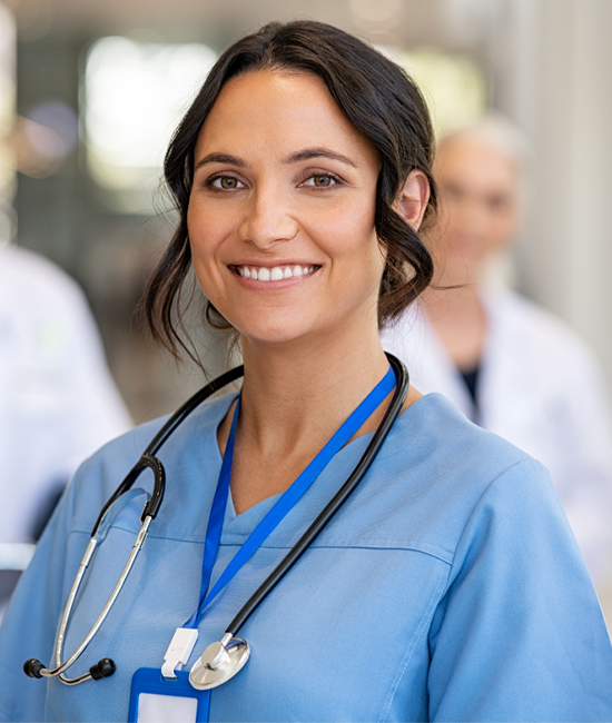 Portrait of Smiling Young Nurse in Uniform With Healthcare Team in Background